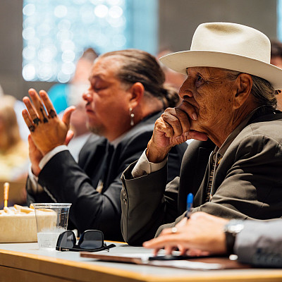 Close up of men sitting at a table listening to a presentation.