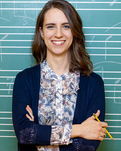Dr. Abrahams standing in front of a music staff board and holding a pencil.