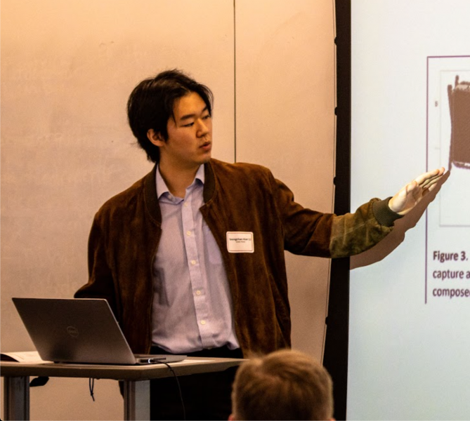 Student presenting a presentation to audience as they point to the screen.