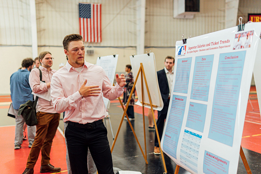 Economic student presenting research to others in the center of the college.